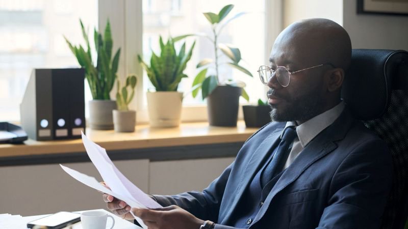 Employee carefully reviewing final paycheck documents at office desk in California