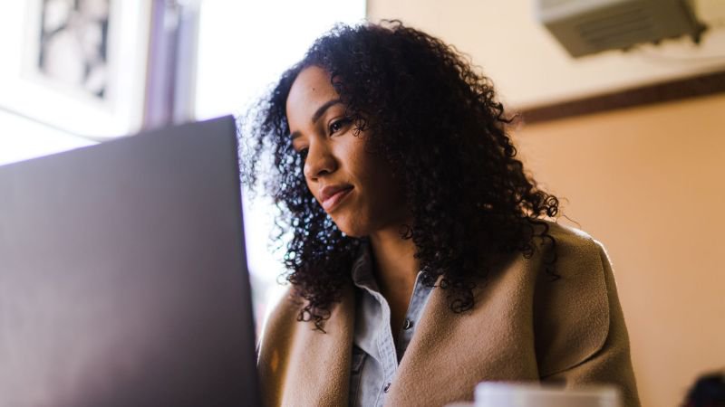 A woman sitting at a desk reviewing information on a computer screen, representing an employee researching her legal options after workplace sexual harassment in California