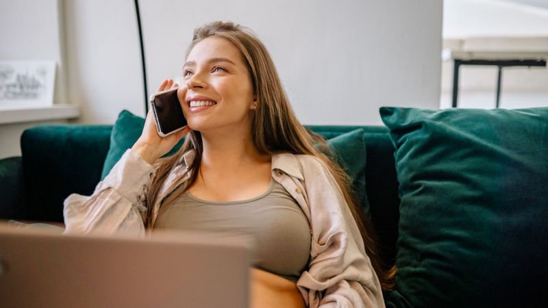 Woman on the phone at home, relaxed and informed about her California paid sick leave rights