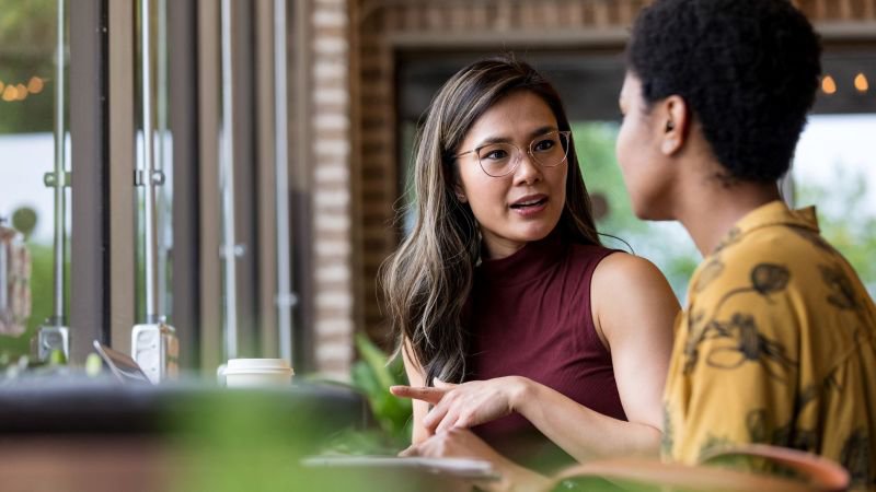 Professional woman in a serious conversation with a colleague at a cafe table