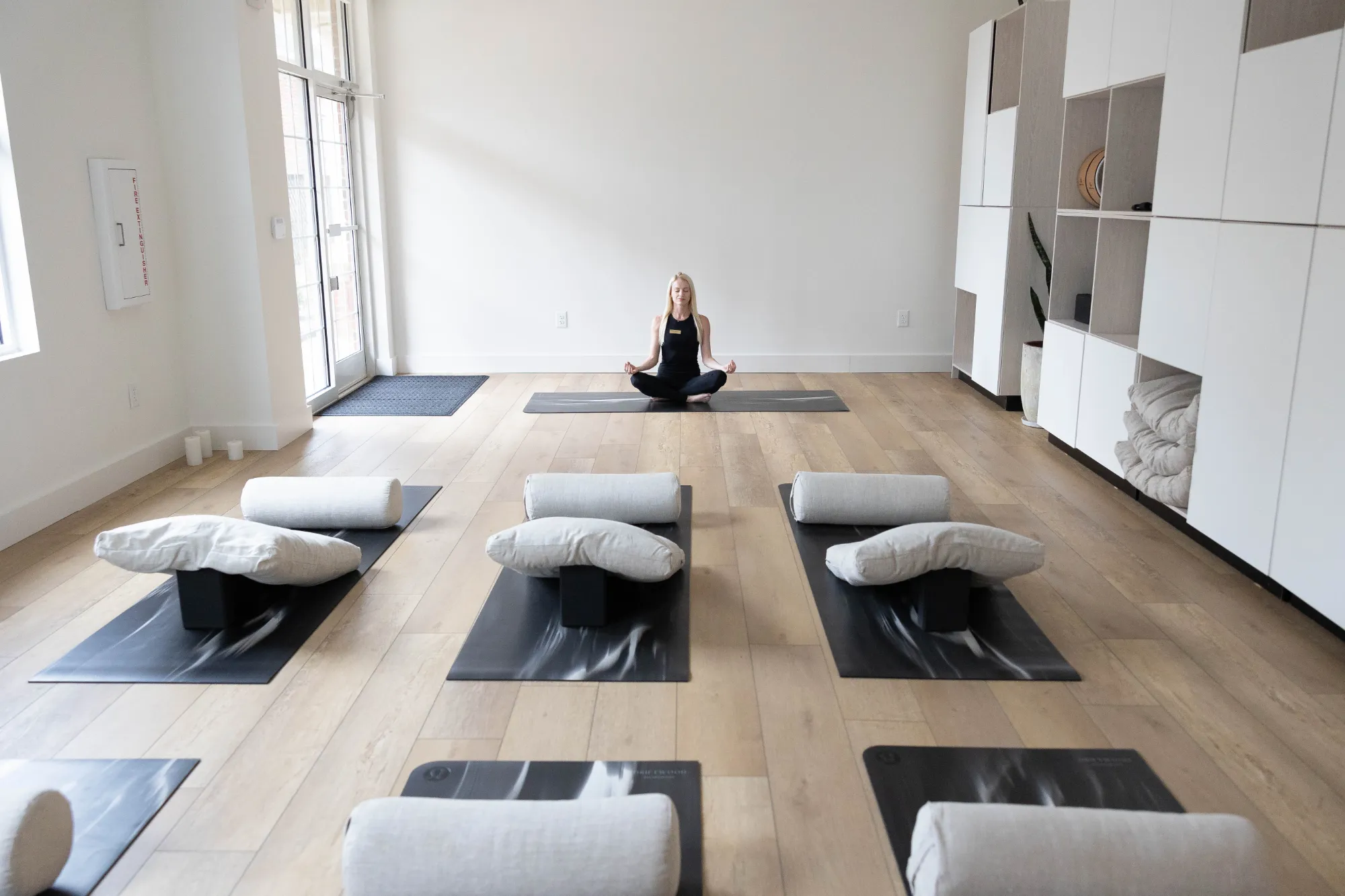A woman practicing yoga in a serene room with white walls, promoting tranquility and mindfulness.