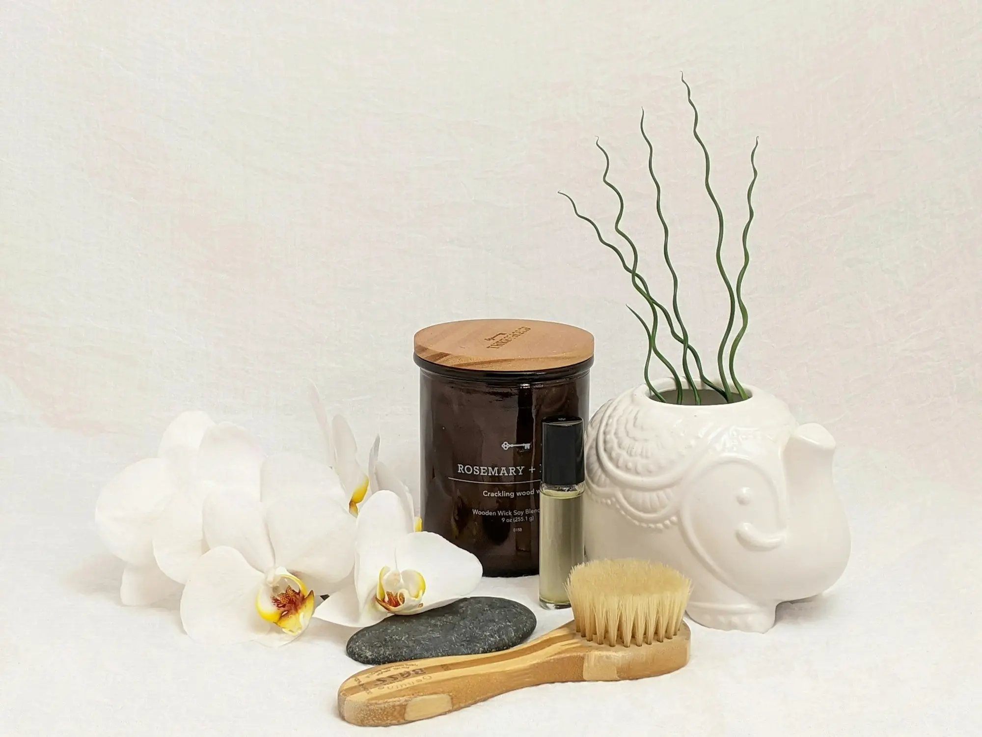 A white elephant candle beside a brush and a small green plant, creating a serene and decorative arrangement.