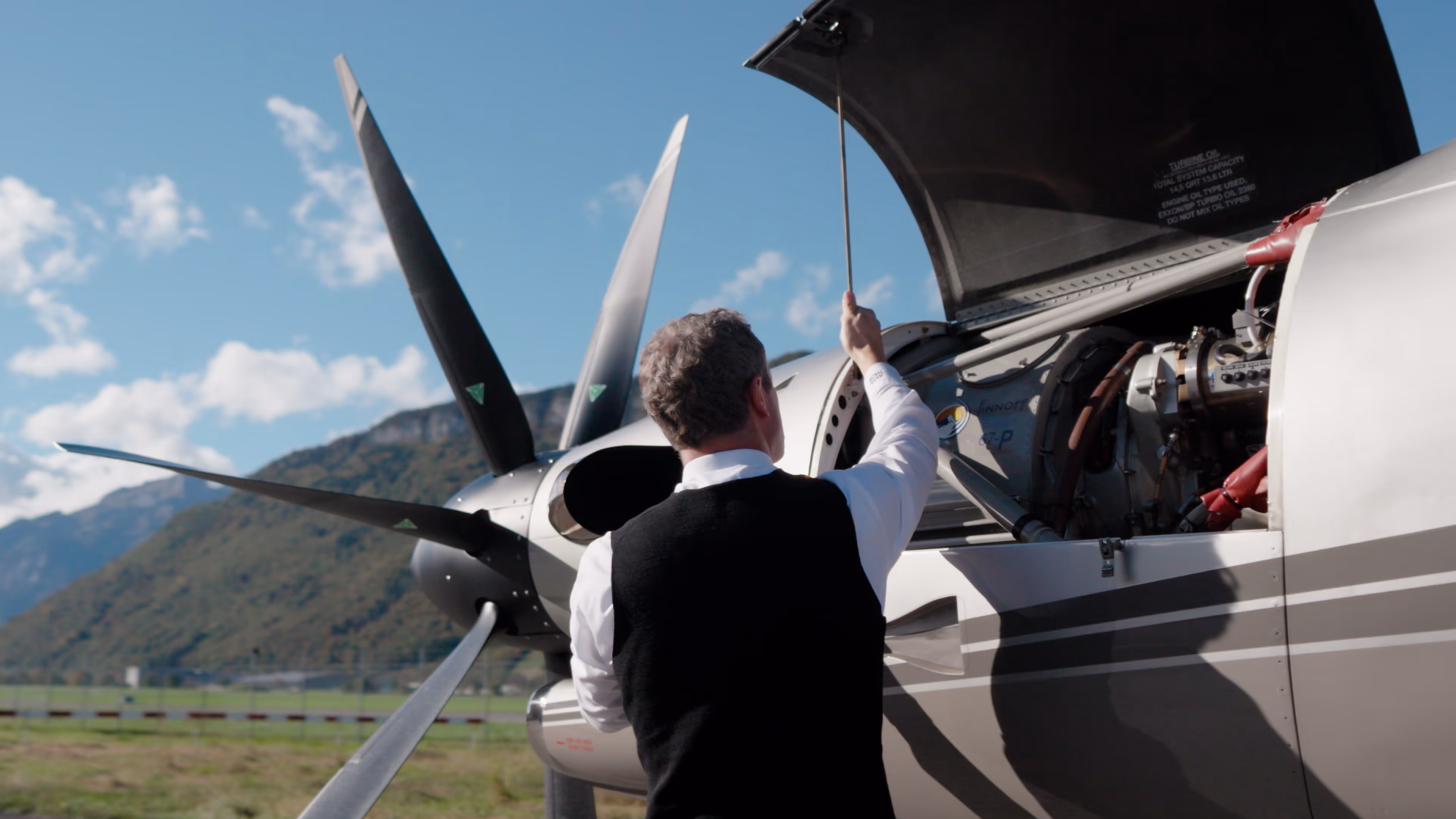 Aircraft owner inspecting Pilatus PC-12 engine with open cowling.