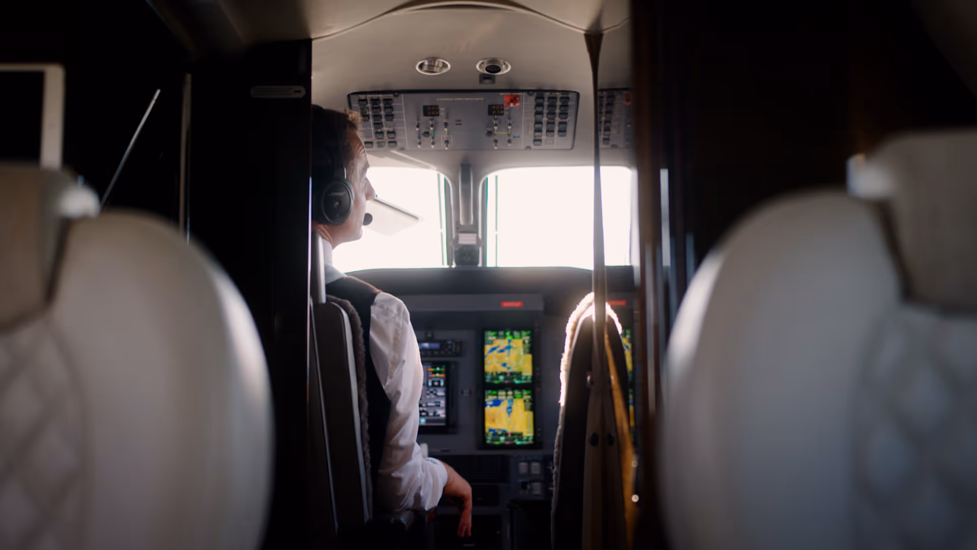 Pilot in cockpit of Pilatus aircraft operating flight controls.