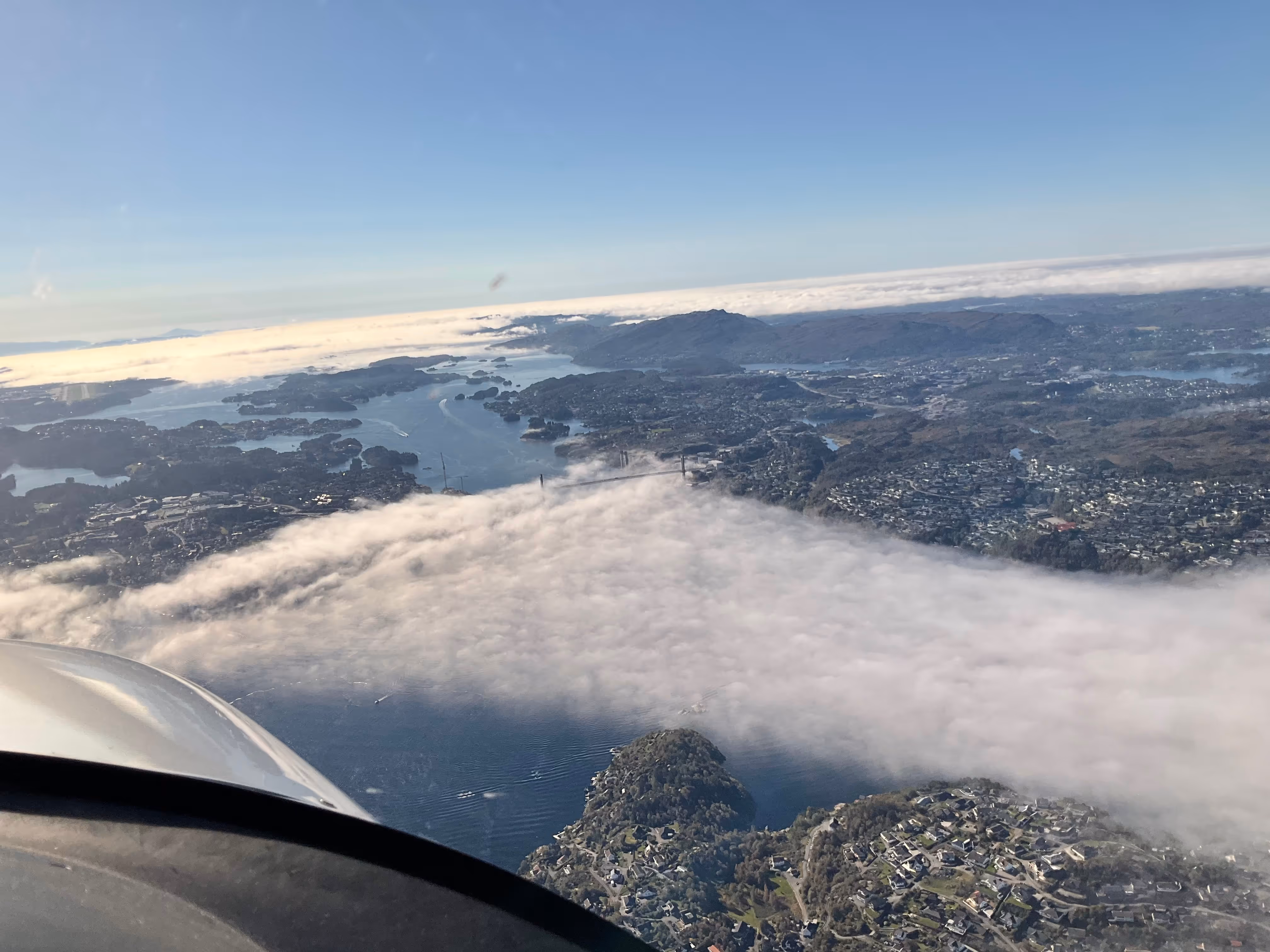 Aerial view of coastline and islands partly covered in fog from cockpit.