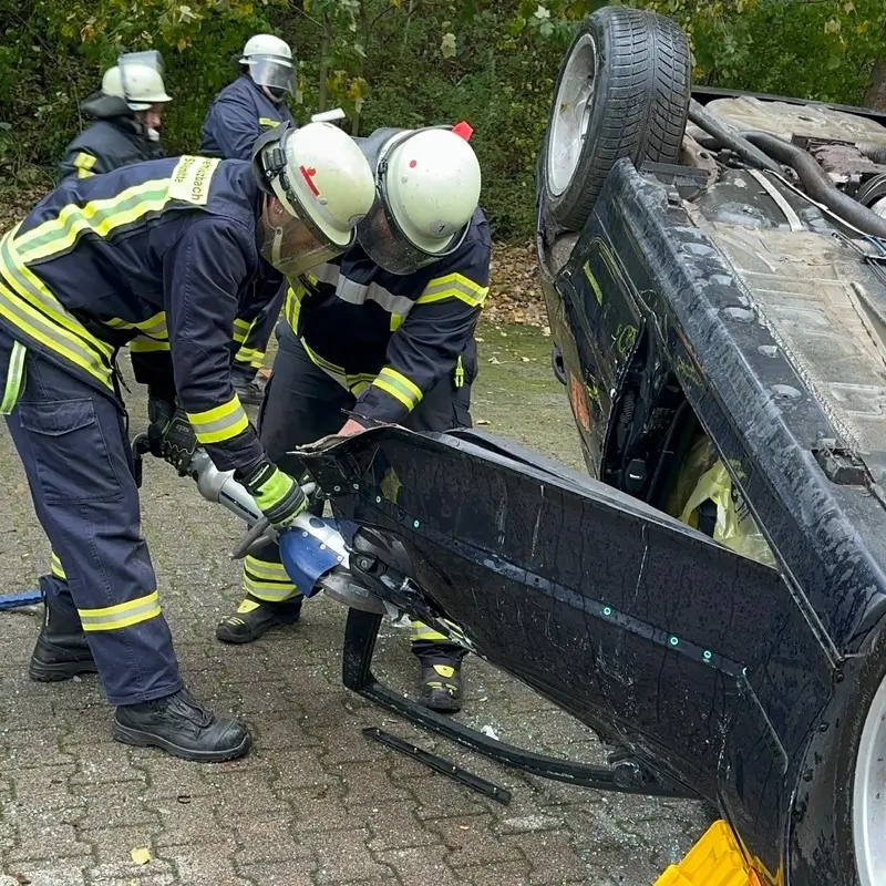 Feuerwehrleute bergen eine Fahrertür eines auf dem Dach liegenden Autos bei einem Unfall. Im Training von Technical Rescue Rheinhessen