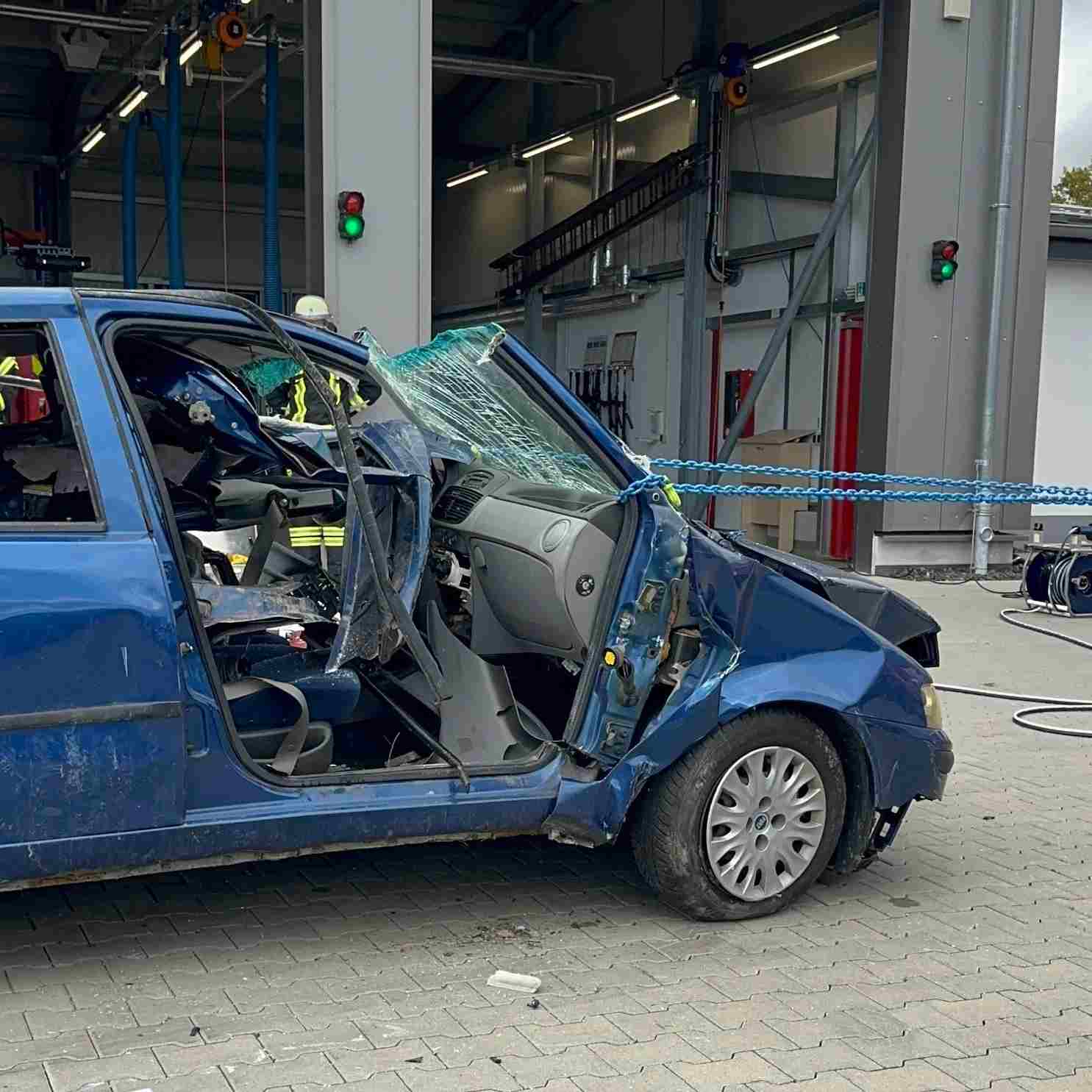 Blaues Auto mit aufgeschnittener Fahrertür und zerbrochenem Frontscheiben-Glas bei einer Rettungsübung. Kettenrettung nach der Oslomethode - Training Technical Resuce RH