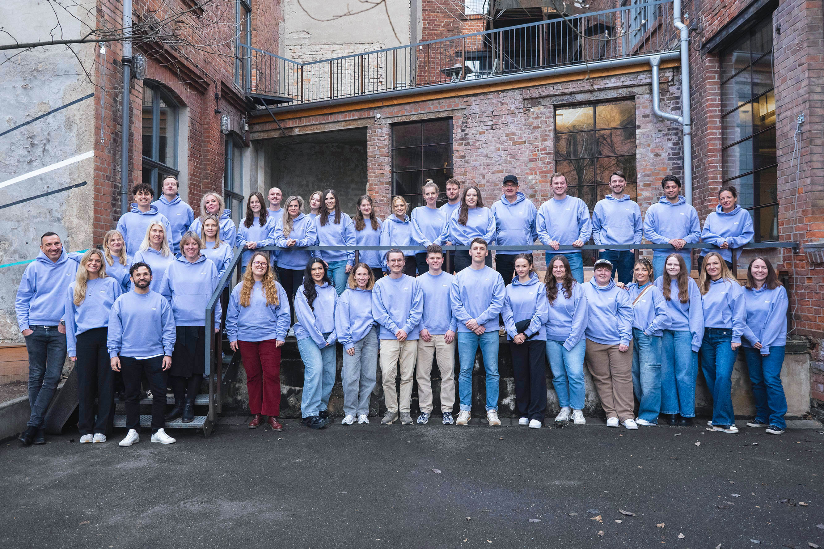 Das MOD-Team bei einem Live-Event in Leipzig. Im Hintergrund ist ein Even Venue im Urban-Farbik-Style zu sehen.