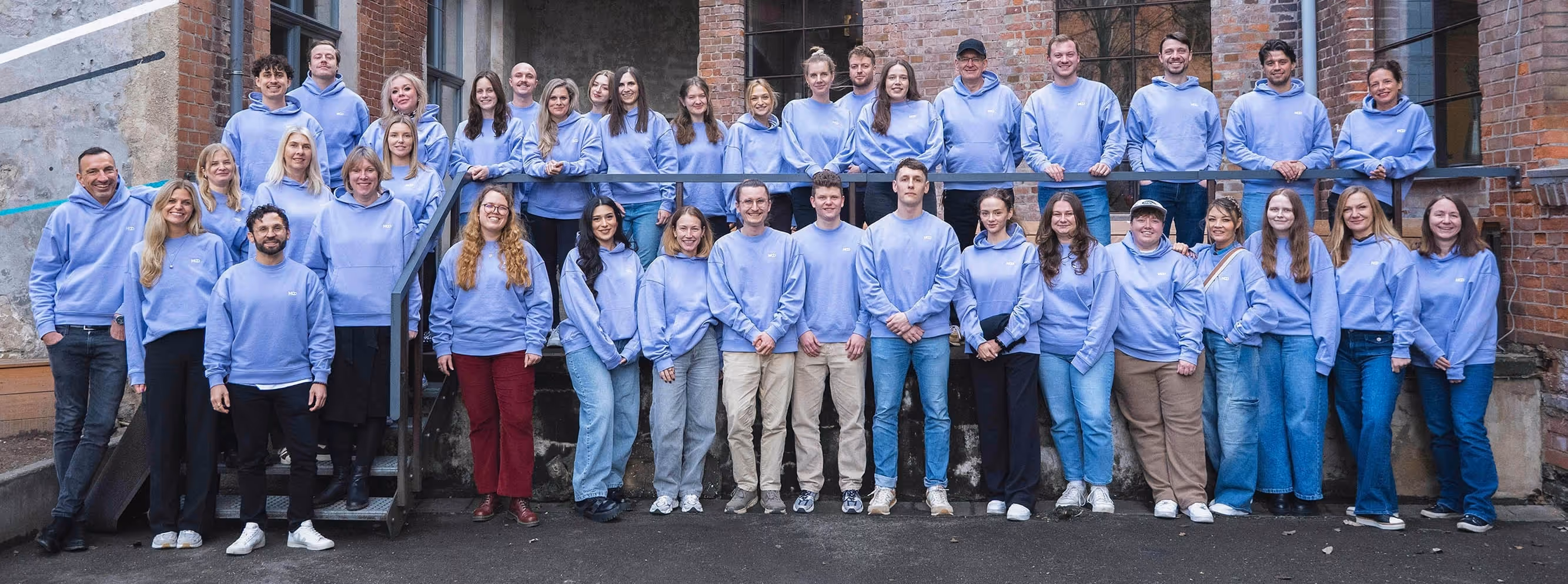 Das MOD-Team bei einem Live-Event in Leipzig. Im Hintergrund ist ein Even Venue im Urban-Farbik-Style zu sehen.