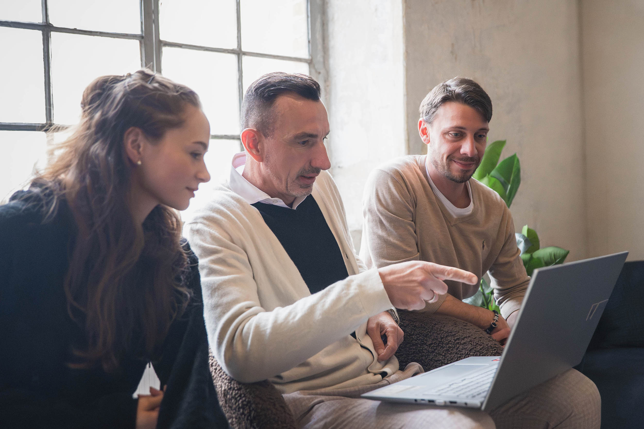 Zwei Person schauen einem SEO-Manager über die Schulter, während er seinen Prozess erklärt