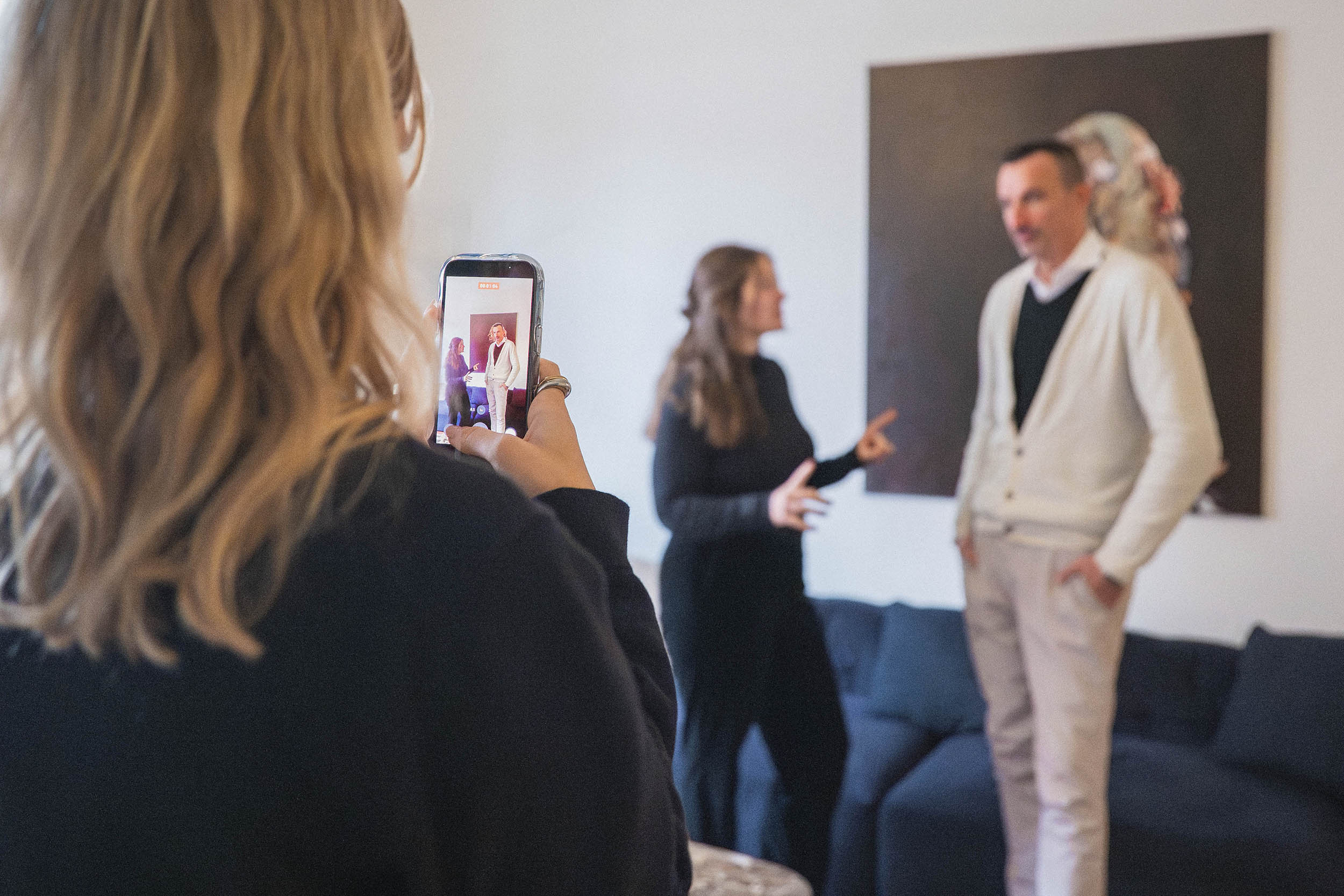 Eine weibliche Person filmt zwei weitere Personen mit ihrem Smartphone für Social Media