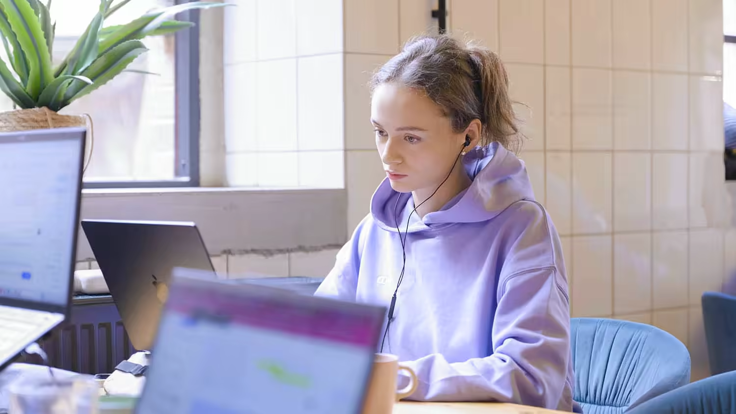 Teilnehmerin mit Kopfhörern arbeitet konzentriert am Laptop, MOD Weiterbildung Digital Sales.