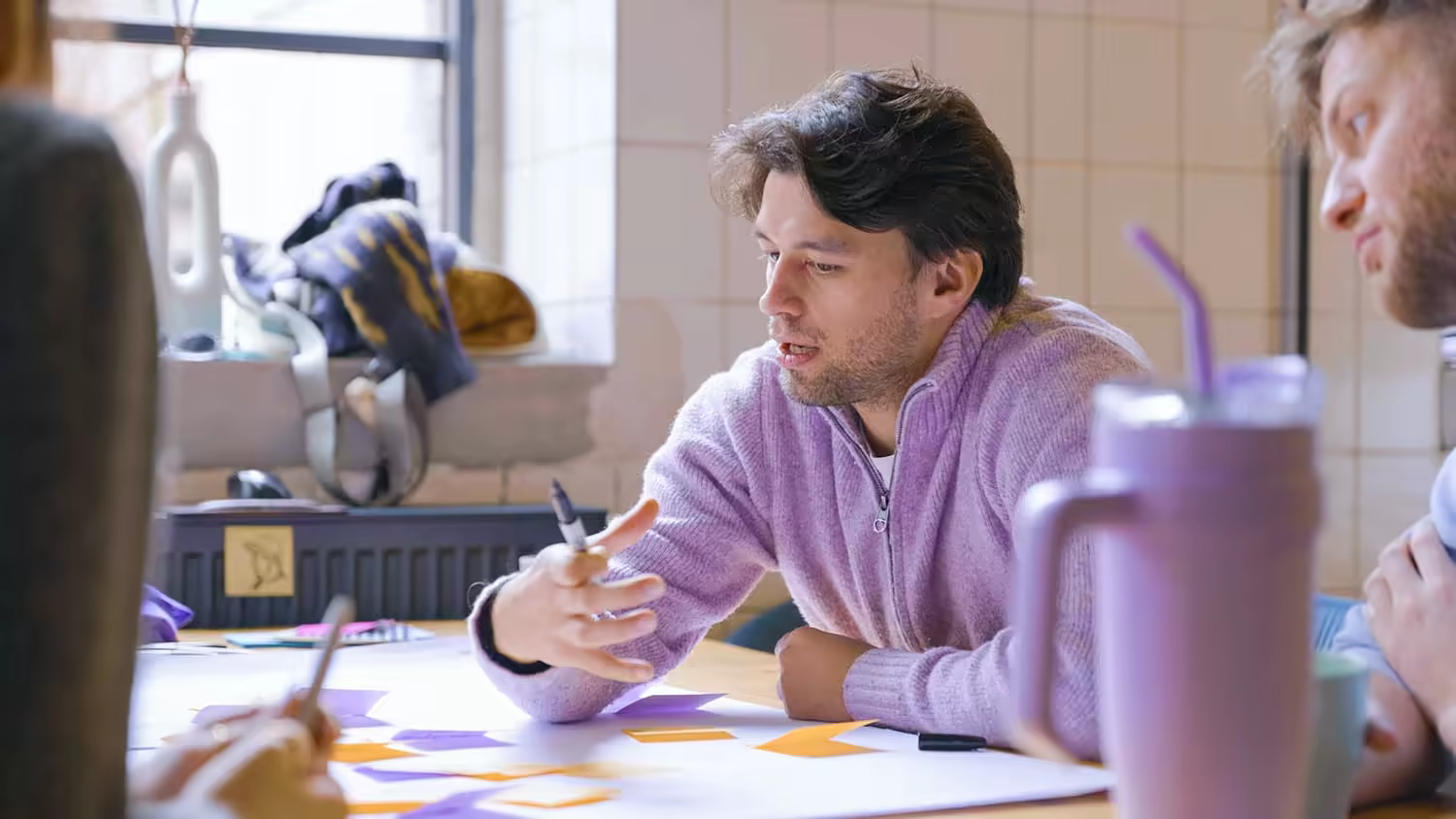 Teilnehmer erklärt am Tisch eine Aufgabe, vor ihm liegen Notizzettel und ein Plakat - Workshop aus der MOD Weiterbildung Digital Sales.