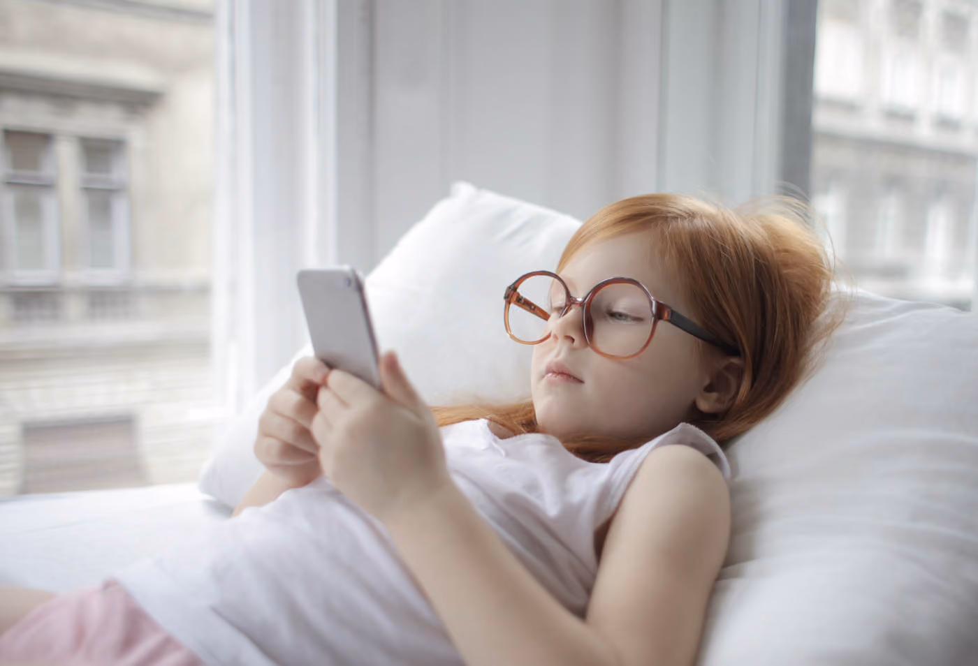 Young Girl Playing on her phone wearing new glasses