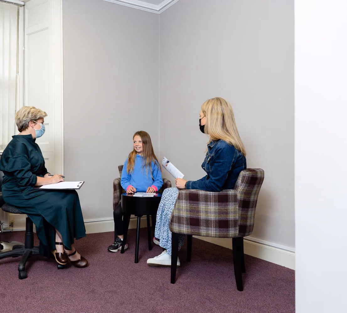 Young girl with optometrist and her mum at local optician