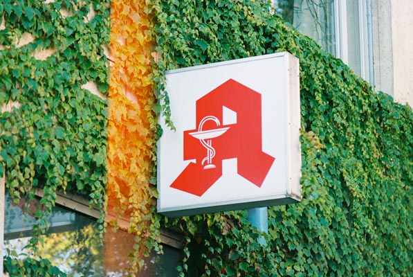 Apothekenschild mit Efeu bewachsener Wand