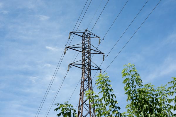 Hochspannungsleitung und Strommast vor blauem Himmel