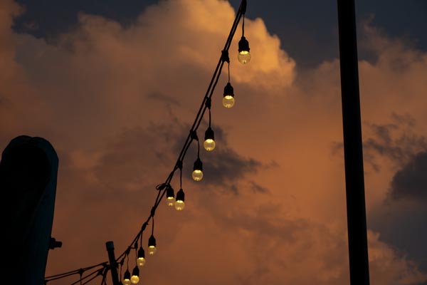 String lights against a dramatic sunset sky