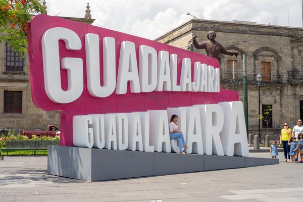 Sitzende Frau auf großen Guadalajara-Buchstaben
