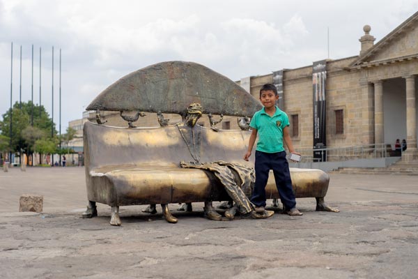 Junge neben kunstvoller Bronzebank in Guadalajara