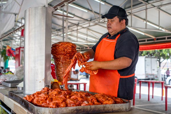 Marinated pork on vertical rotisserie at food stall