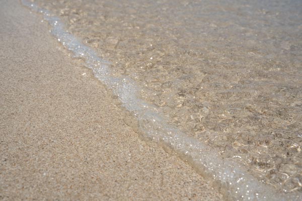 Feine Wellenbläschen am sandigen Tropenstrand