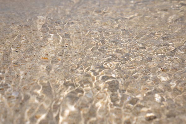 Sonnenlicht auf flachem Wasser über sandigem Grund