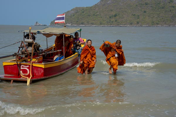Junge buddhistische Mönche steigen aus Boot ans Ufer