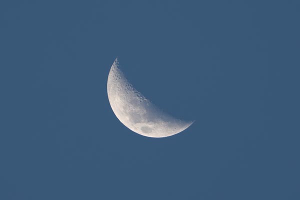 Sichelmond mit Kratern am klaren blauen Himmel