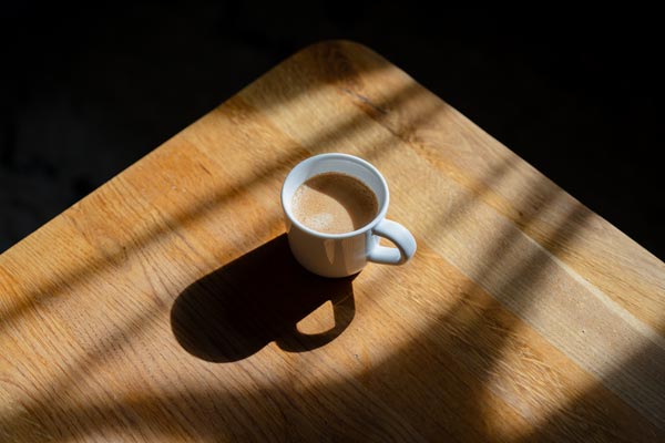 White coffee mug on sunlit wooden table