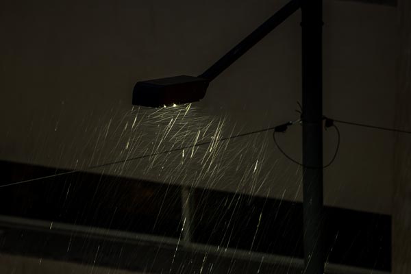 Straßenlaterne erhellt fallenden Regen bei Nacht