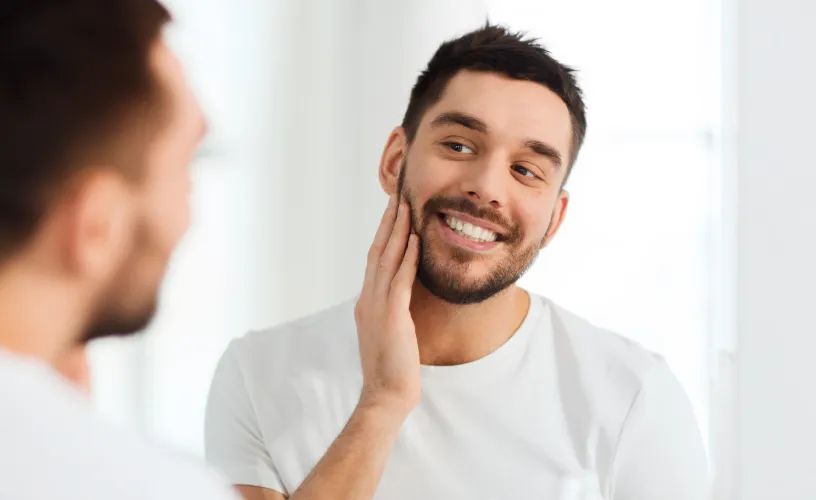 Man looking at his teeth and cheek in the mirror