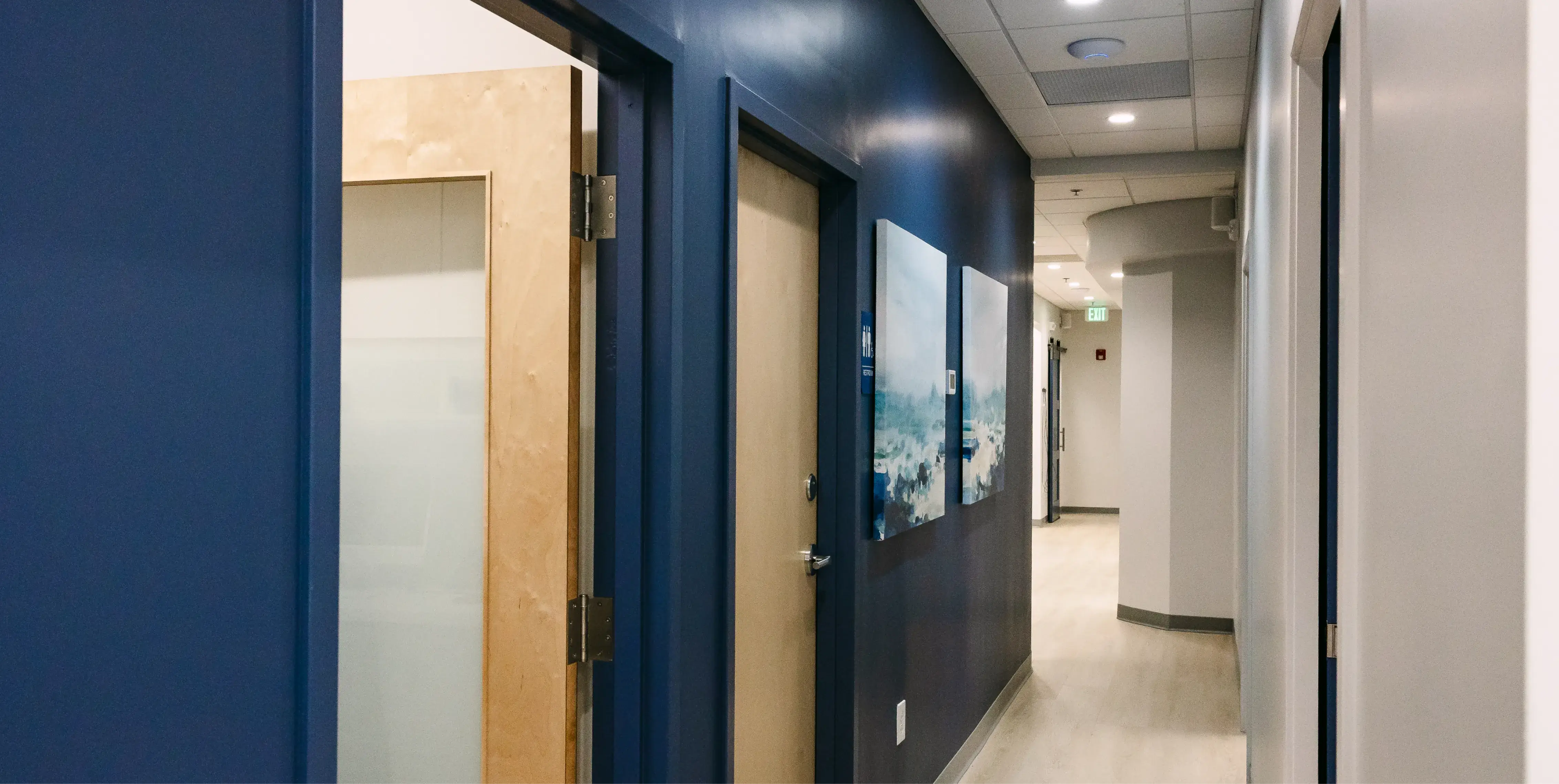 A hallway with blue walls and closed wooden doors on each side.