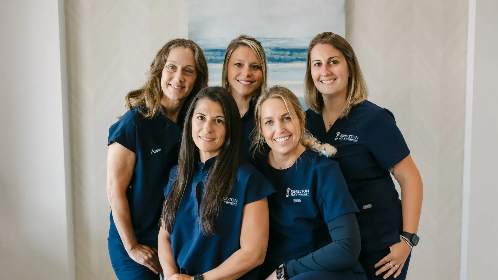 Five women in matching uniforms smiling and posing together indoors.