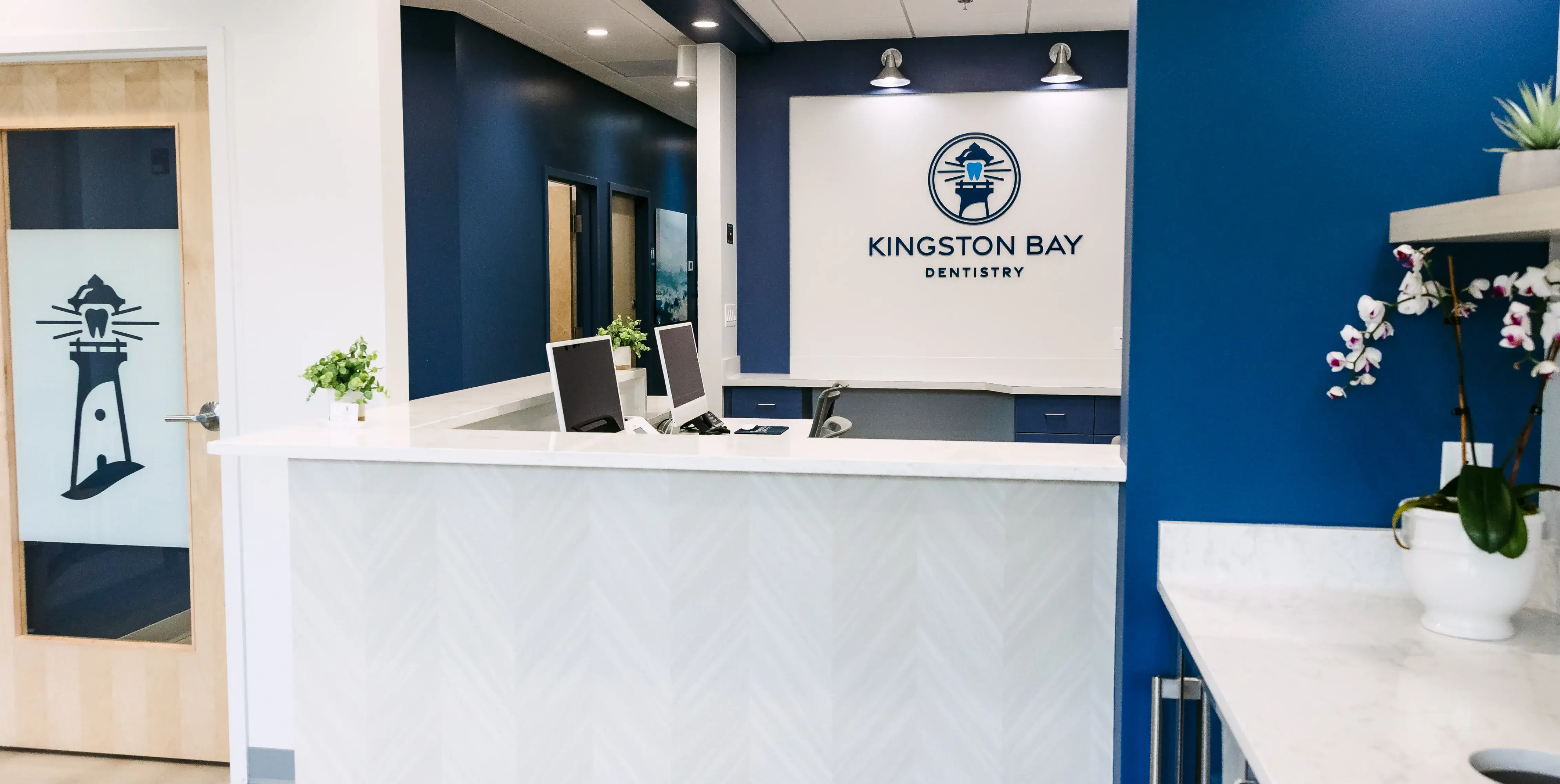 Dental office reception area with a white desk, computers, and a sign reading "Kingston Bay Dentistry."