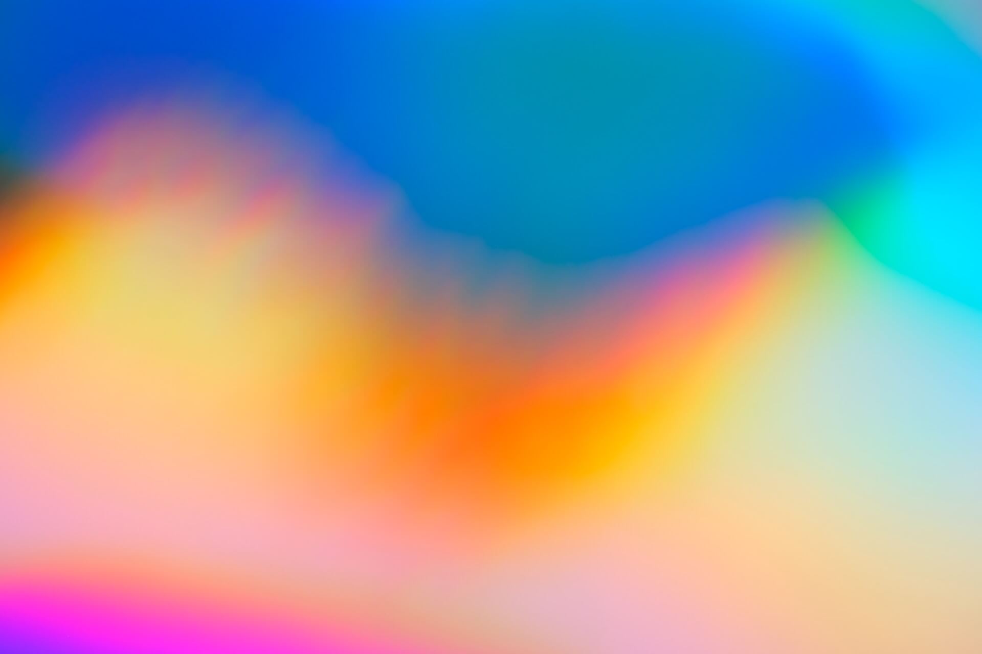 An abstract gradient with blues, oranges, yellow, and pinks/purples