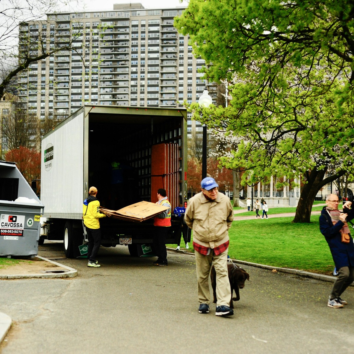 Professional movers loading a large furniture piece into a moving truck near a residential building, representing heavy furniture movers near me.