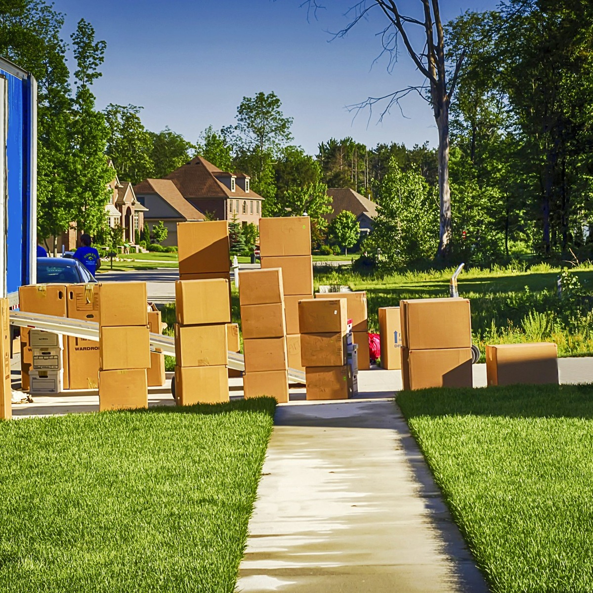 Moving boxes and household belongings arranged beside a moving truck in a residential neighborhood, representing heavy furniture movers in Boynton Beach, FL.