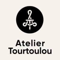 Atelier Tourtoulou logo with stylized white initials A and T inside a black circle above the brand name.