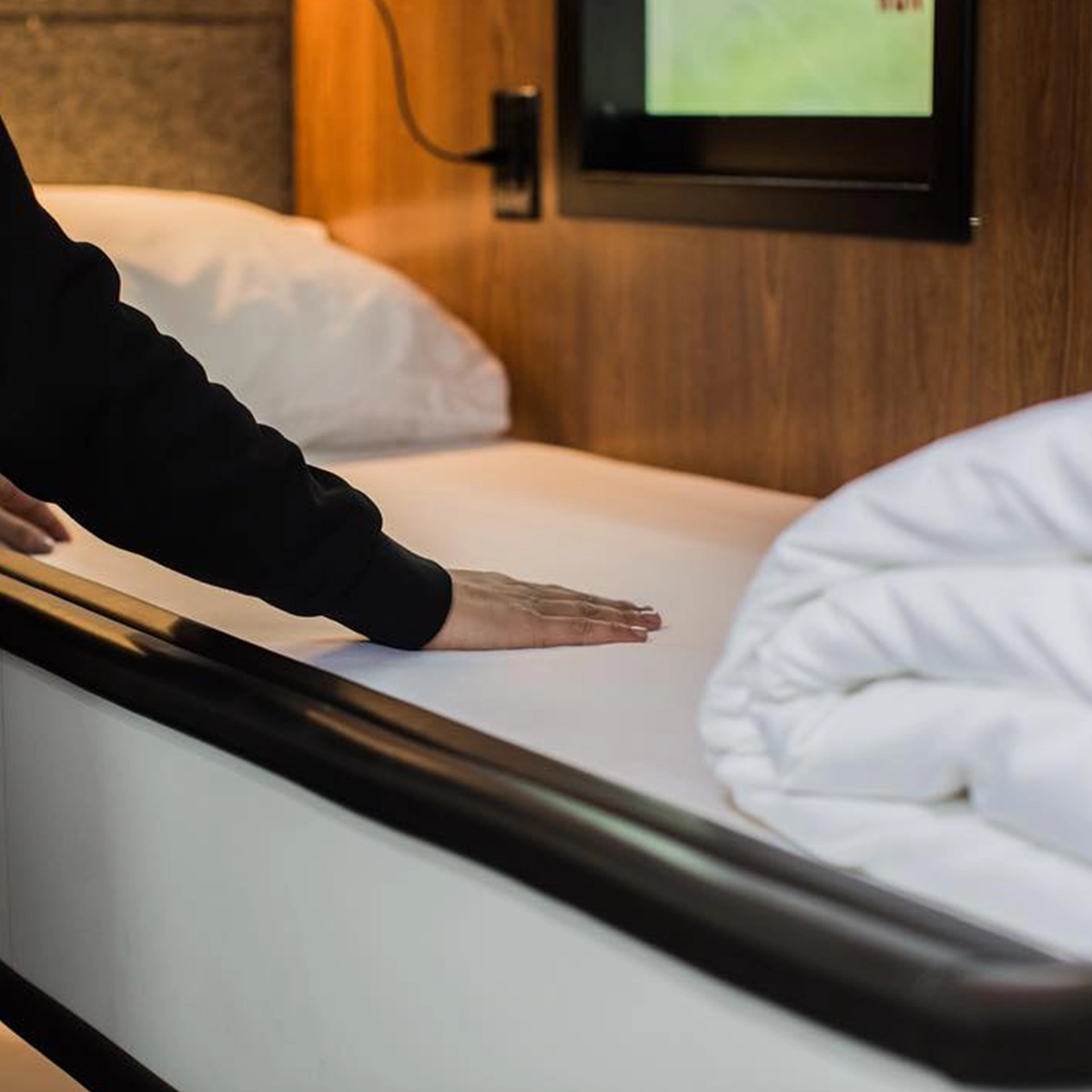 Bedding smoothed in a Cabin pod beside the window and reading light