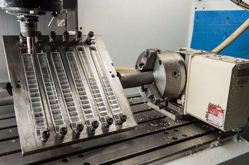 Close-up of a CNC milling machine working on a metal part with multiple parallel slots.