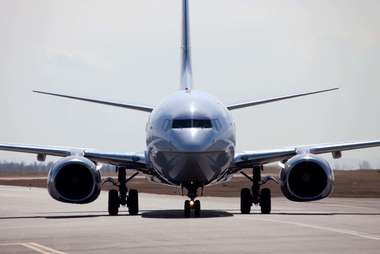 Front view of a commercial airplane on a runway with engines and landing gear visible.