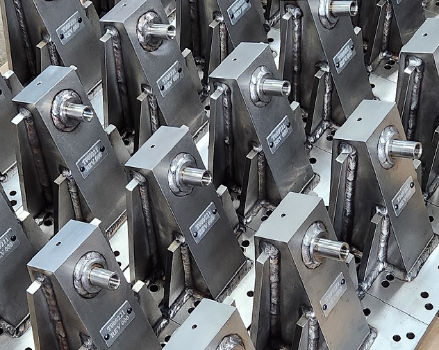 Close-up of mechanical parts including a white plastic bracket, a yellow gear, and a flexible brown component on a blue surface.