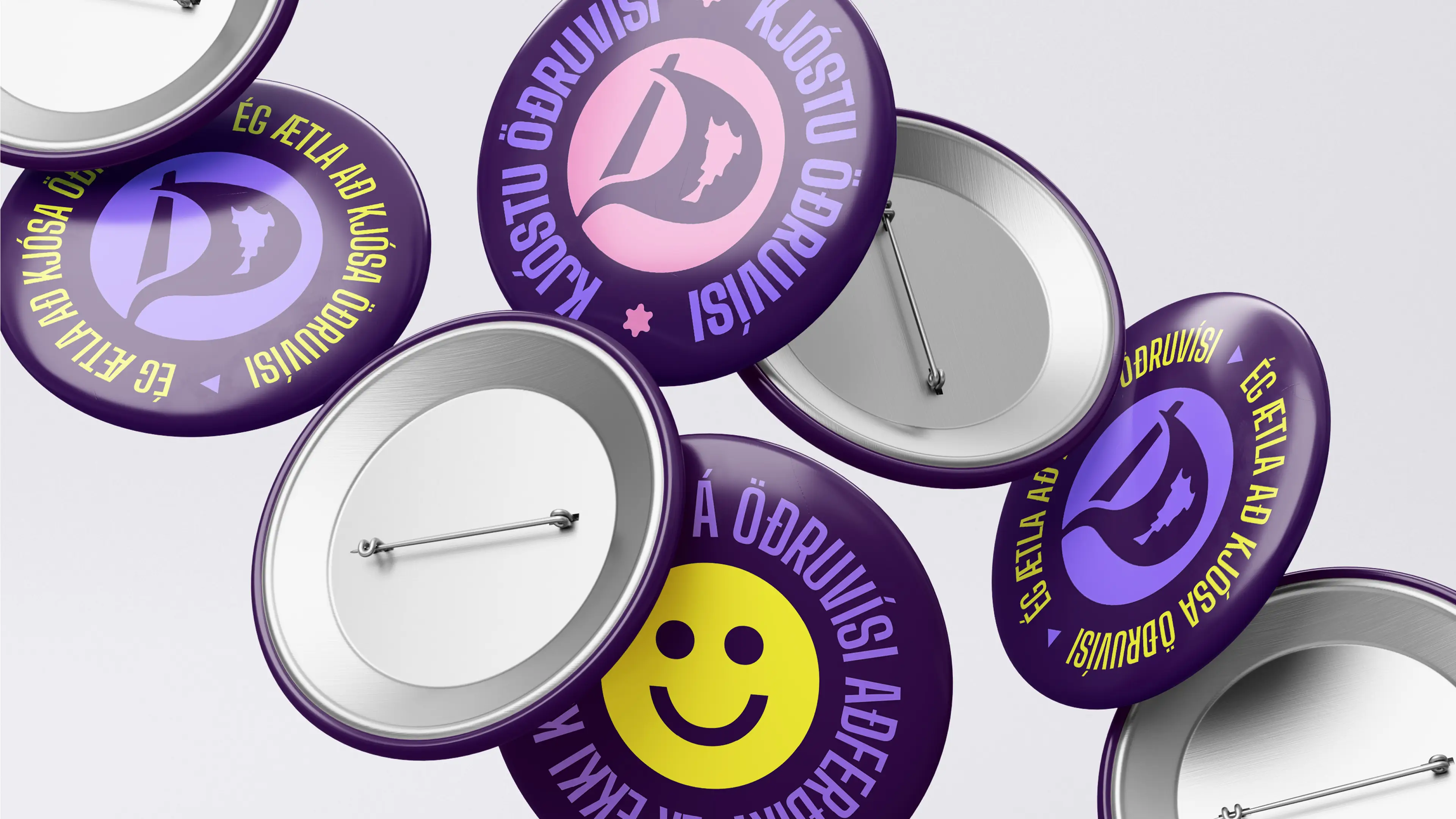Colorful enamel pins feature smiley faces and Icelandic phrases in vibrant purple, pink, and yellow hues.