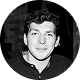 Black and white headshot of a smiling young man with short hair wearing a dark jacket over a collared shirt.