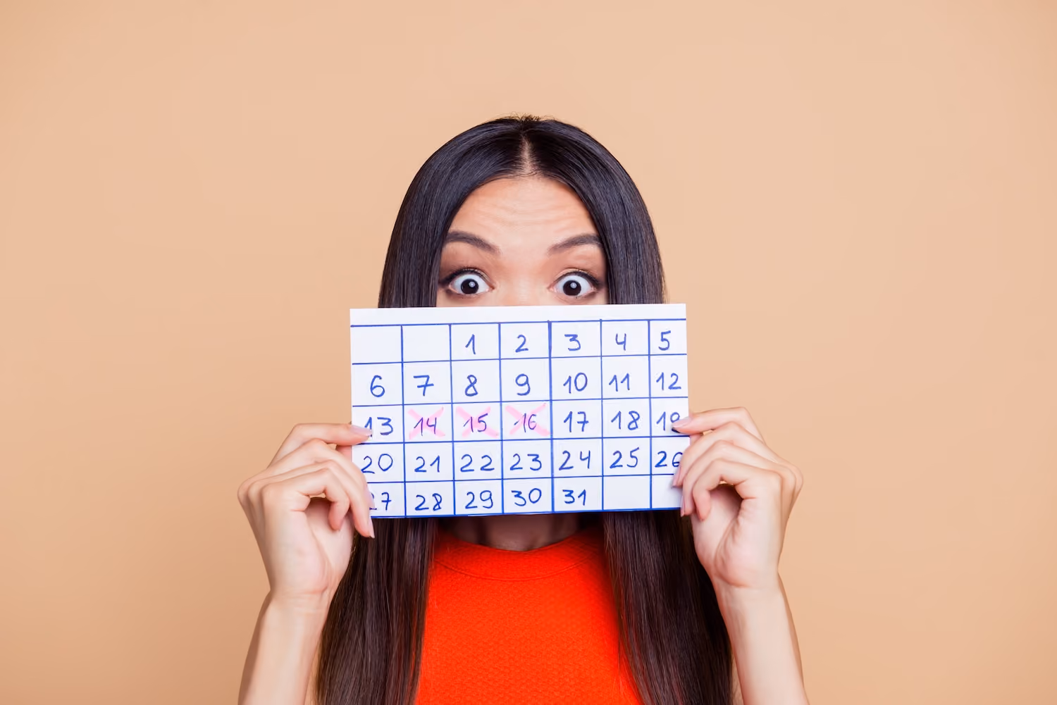 Woman holding a calendar with days crossed off partially obscuring her face