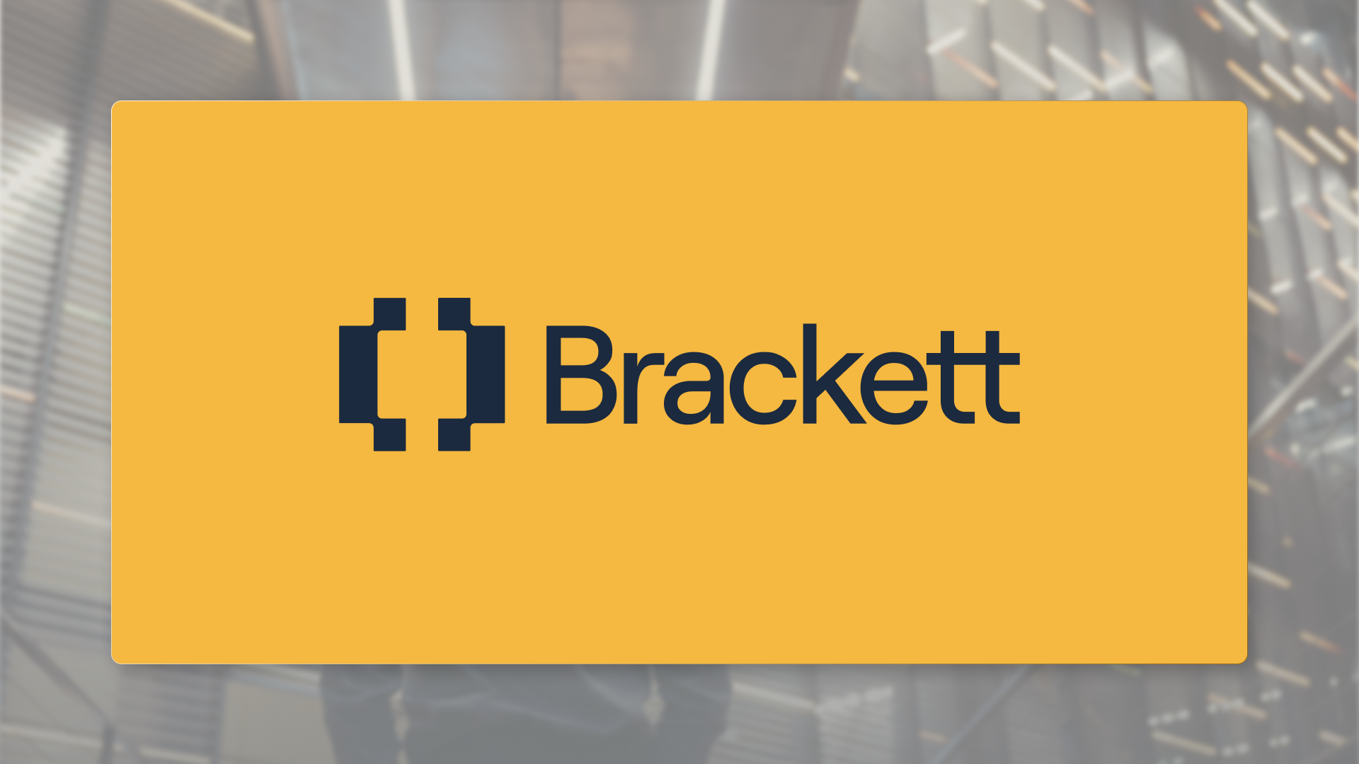 The brackett logo in dark navy on a solid goldenrod colored rectangle. A glassy, blurred photo of a modern architectural interior is in the background.