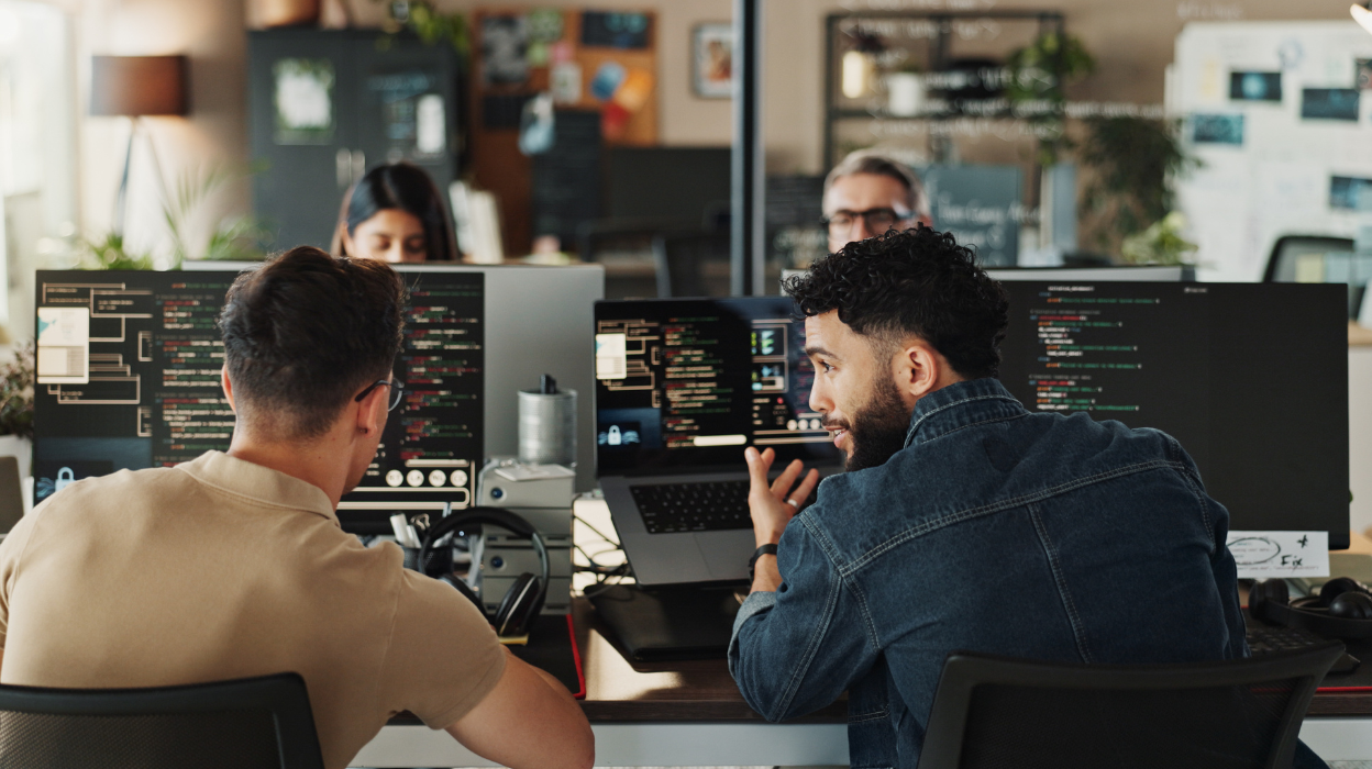 Two colleagues collaborate while workingon computers in a modern office environment.