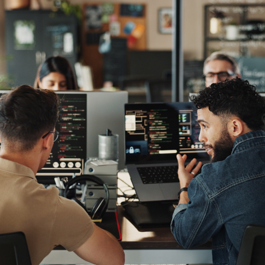 Two colleagues collaborate while workingon computers in a modern office environment.