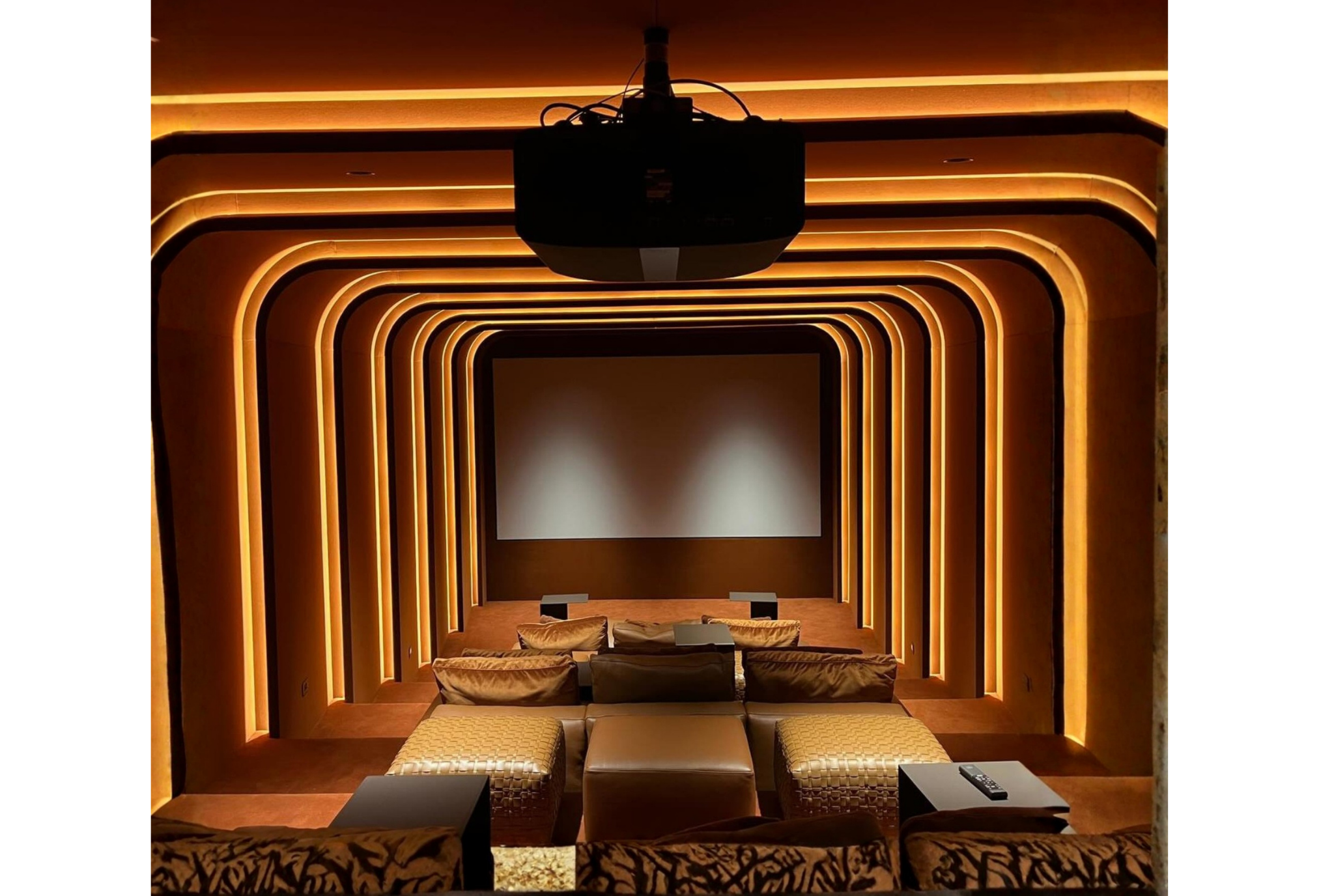 Modern home theater with warm ambient lighting, a large projection screen, and comfortable cushioned seating.